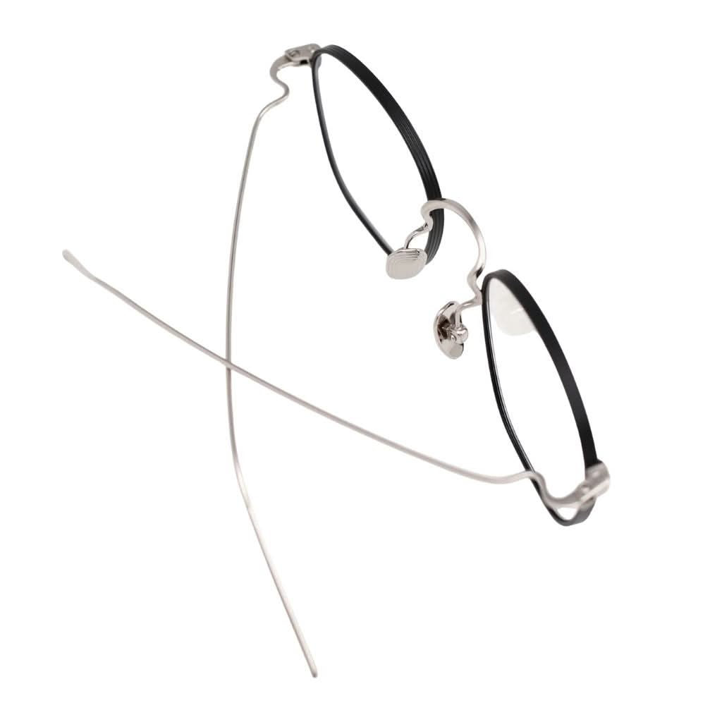 Detailansicht der AKILA Osiris 02 – feine Titanverarbeitung in Schwarz und Silber, minimalistische Designerbrille bei Optik Bartholomä München
