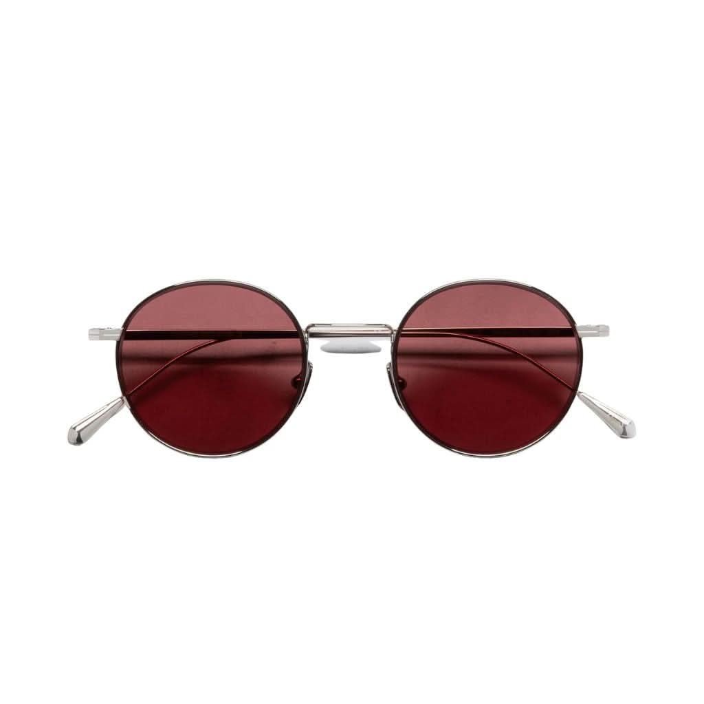Detail der AUSN 0001 – präzise Swiss-Alloy-Fassung, rot-rosa Gläser, edles 18K Weißgold-Rhodium-Finish bei Brillen Schneider in München.