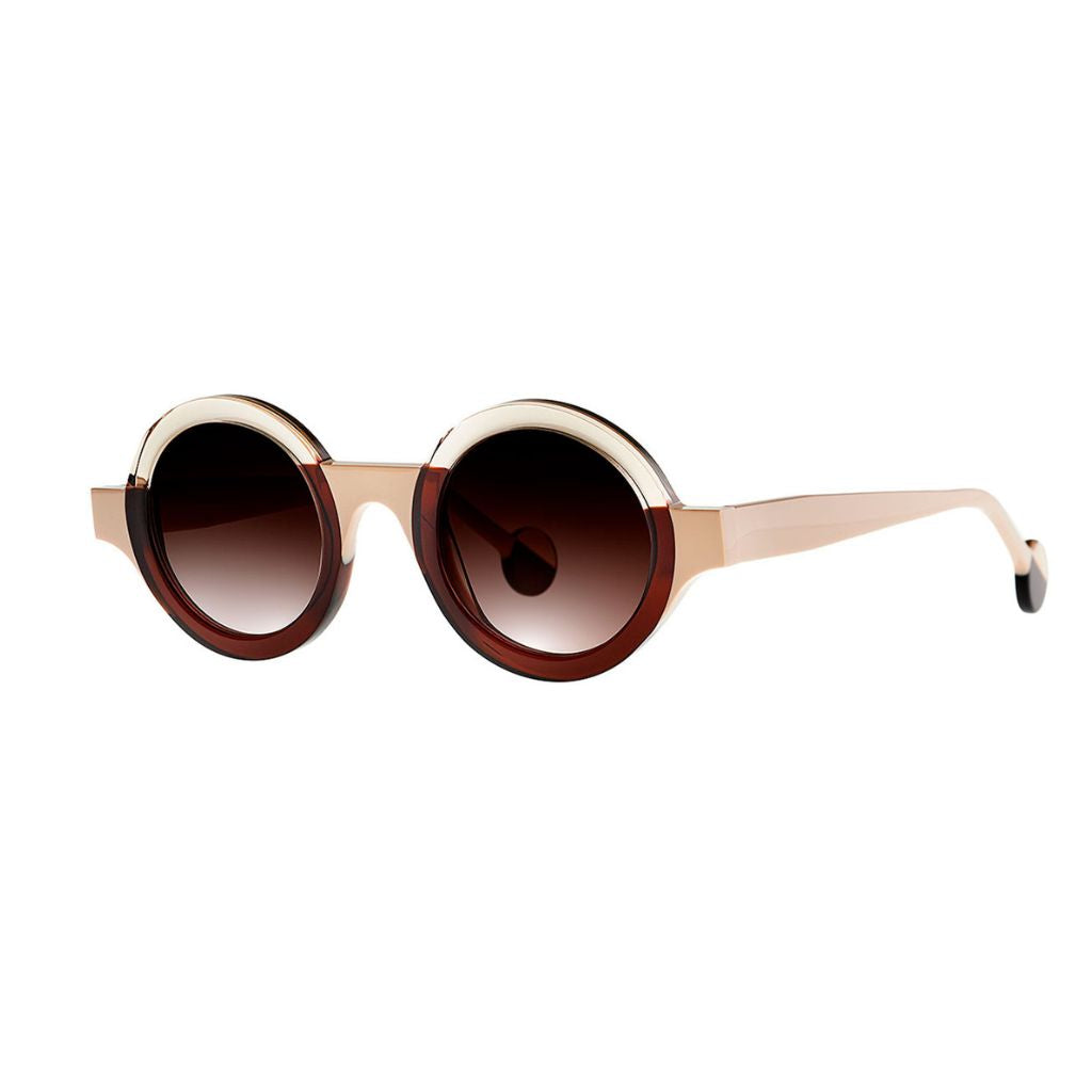 Die Sonnenbrille KUBISME 11 in braun-weiß gehalten mit stilvollem Design von THEO EYEWEAR, abgebildet vor einem neutralen Hintergrund – erhältlich bei BRILLEN SCHNEIDER in München.