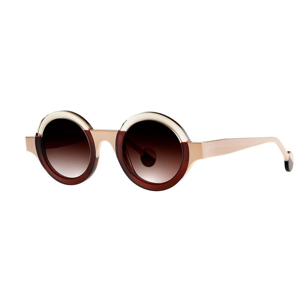 Die Sonnenbrille KUBISME 11 in braun-weiß gehalten mit stilvollem Design von THEO EYEWEAR, abgebildet vor einem neutralen Hintergrund – erhältlich bei BRILLEN SCHNEIDER in München.